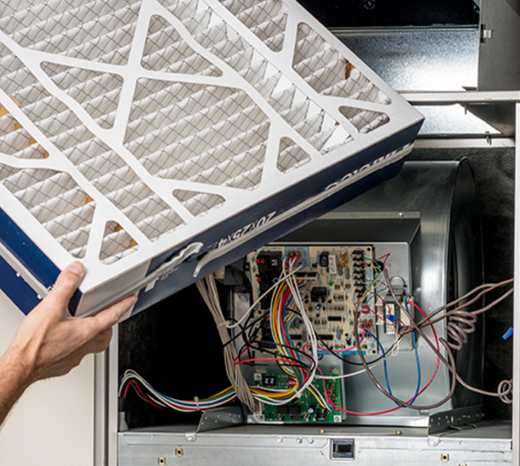 A zoomed in image of a heating technician replacing a furnace filter.
